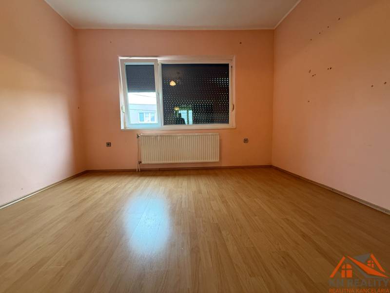 A room in a family house with a wooden decor floor and pink walls.