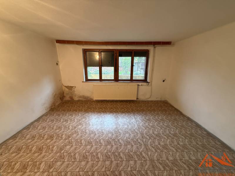 A room in a family house with a wooden decor floor and a window, slightly damaged walls.