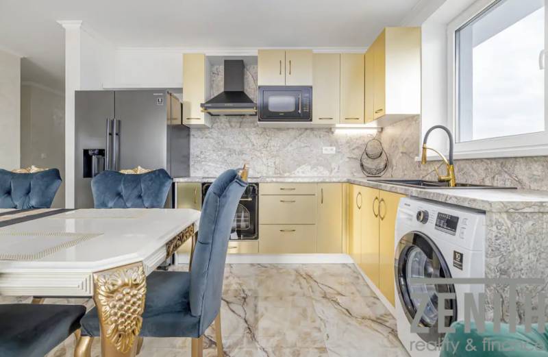 A kitchen in a family house with a marble floor, gold elements, and blue chairs.