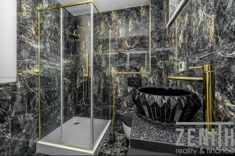 Luxurious bathroom with black marble and gold accessories in a family house.