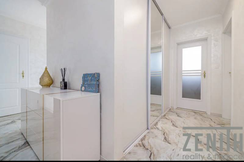 Interior of a family house with white furniture and a marble-patterned floor.