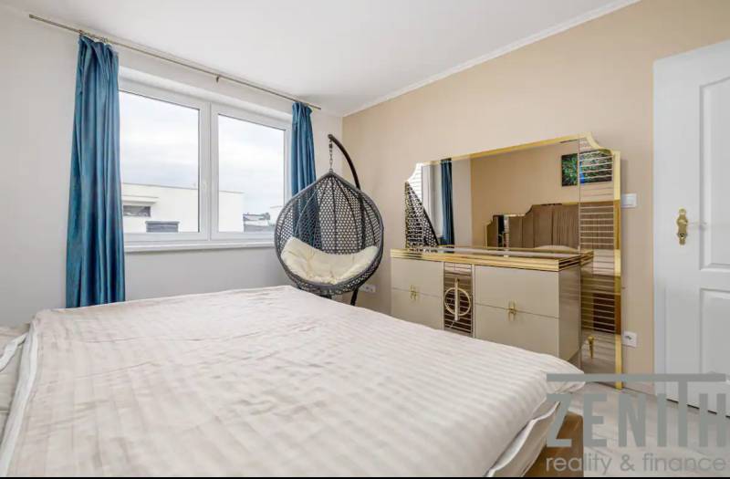 A bedroom in a family house with a bed, a wardrobe, and blue curtains.