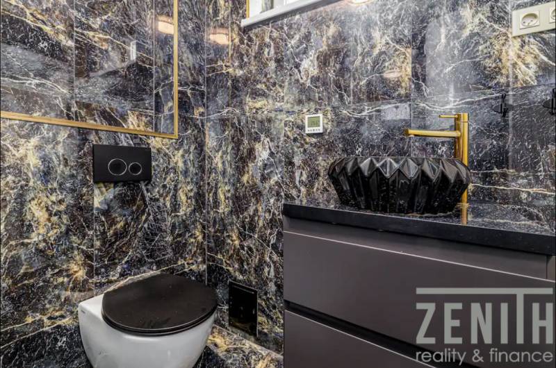 A bathroom in a family house with a black toilet and a marble sink.