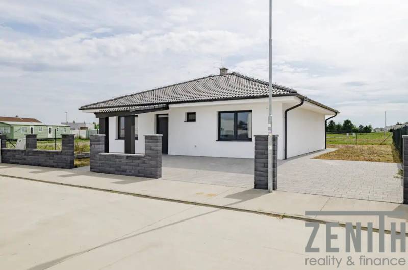 A family house in Hrubá Borša with a white facade and a dark roof, brick fencing.