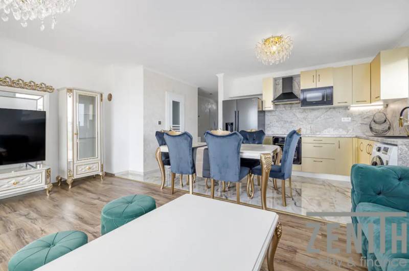 Living room in a family house with a kitchen, marble decor, and wood-patterned flooring.