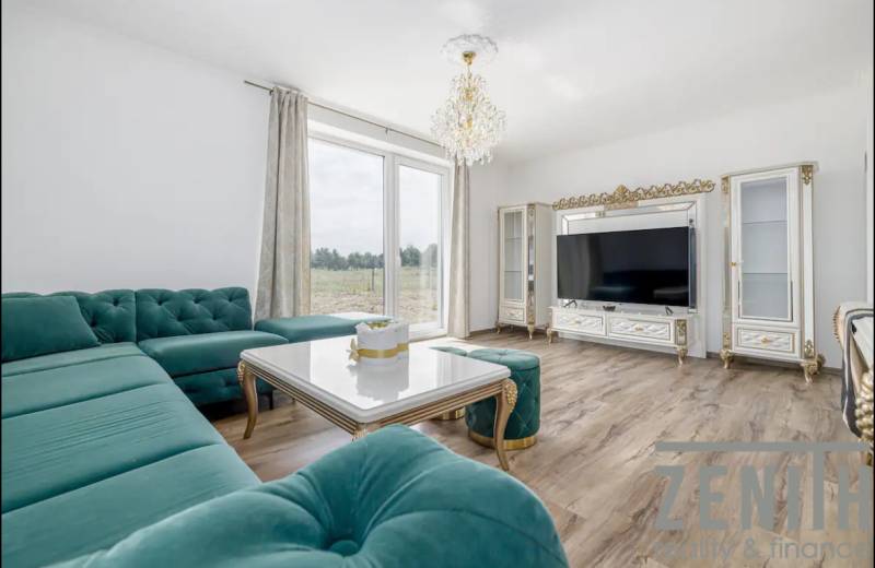 A spacious living room in a family house with a corner sofa and a wooden-patterned floor.