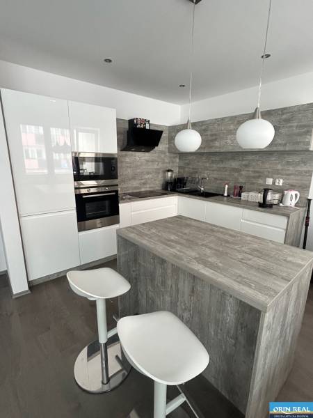 A kitchen in a 2-room apartment with a kitchen island and a floor with a wooden decor.
