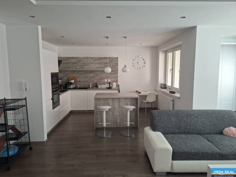 Living room with kitchen in a two-room apartment with a wooden decor floor.