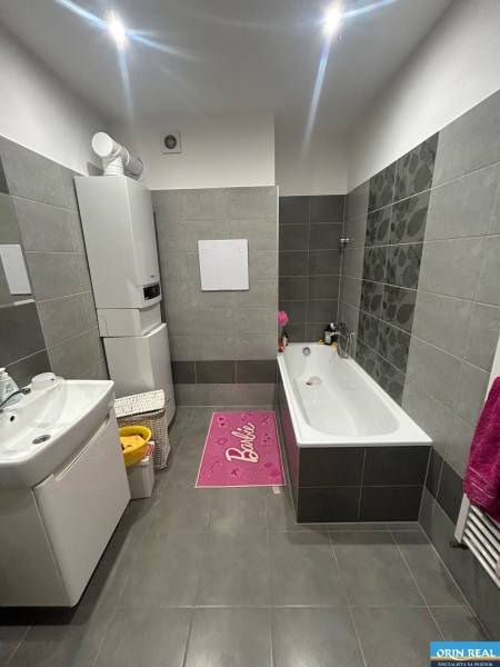 Bathroom in a 2-room apartment with gray tiles, a bathtub, and a sink.