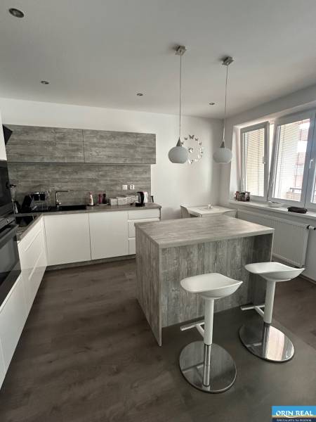 A kitchen with seating, white cabinets, and wood-patterned flooring in a 2-room apartment.