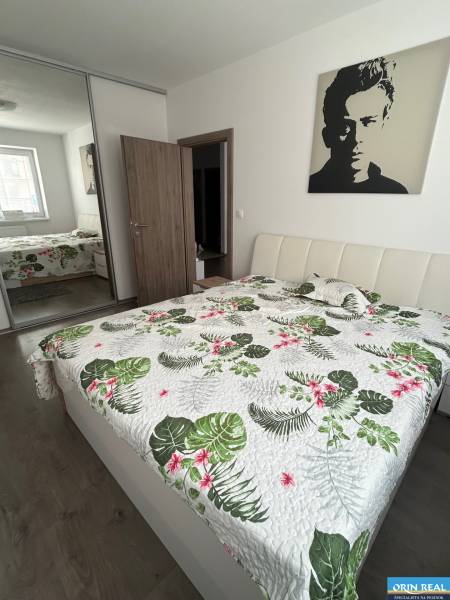 Bedroom in a 2-room apartment with a double bed and a mirrored wardrobe on a wooden-decor floor.