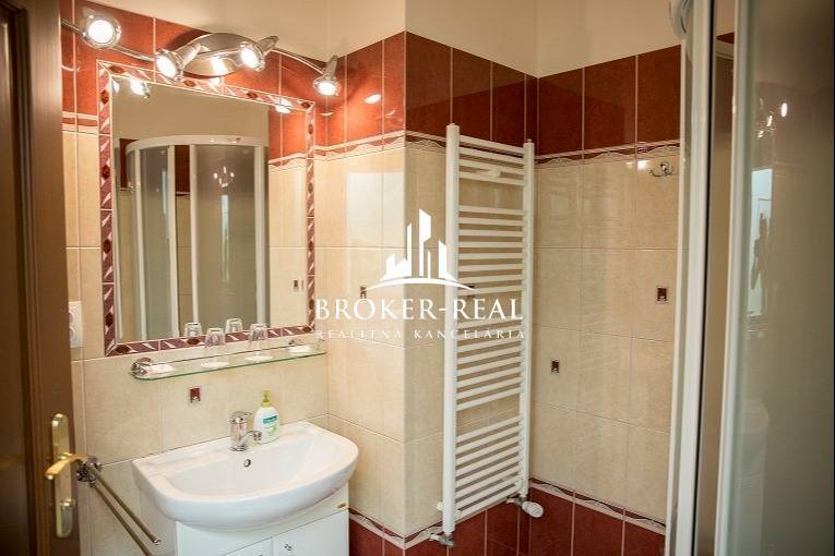 A bathroom with a sink, shower, and ladder radiator in hotels and guesthouses.
