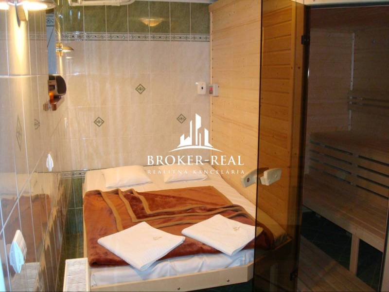 A hotel room with a bed and an adjoining sauna, rustic wooden interior.