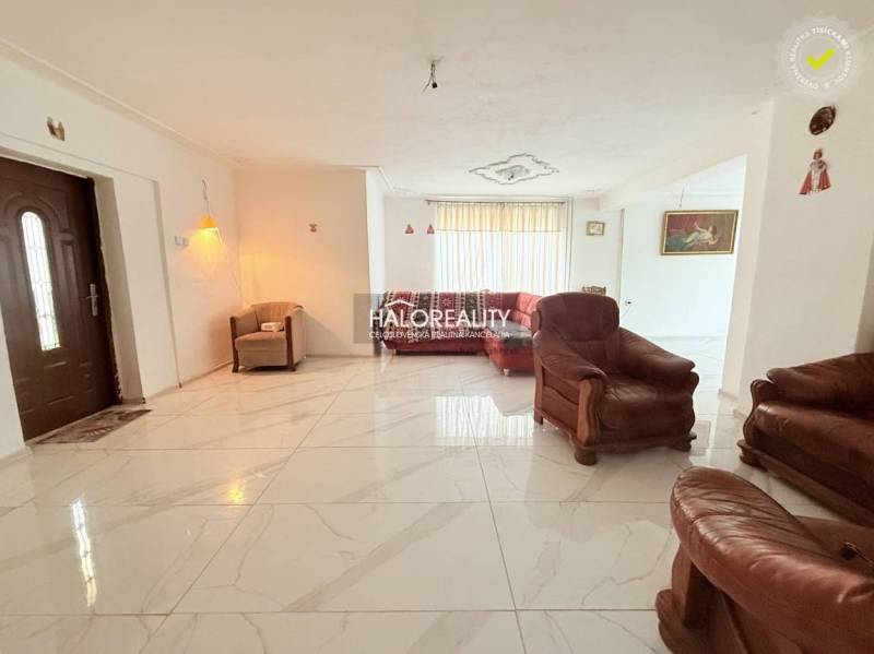 A spacious living room in a family house with comfortable leather furniture and fresh tiles.