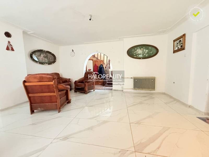 The interior of a family house with a white floor and brown furniture, decorative paintings on the walls.