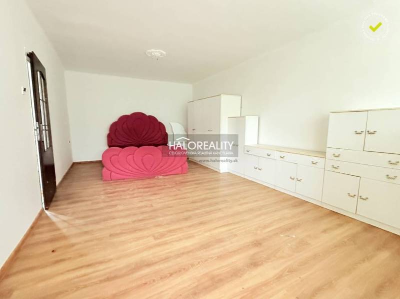 A room with a bed, white furniture, and a wooden decor floor in a family house.