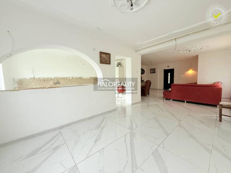 The interior of a family house with a white floor and a red sofa, open space, arched details.