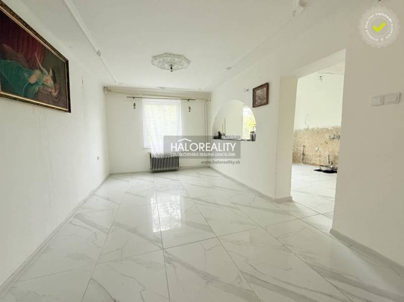 A living room in a family house with white walls and marble flooring.