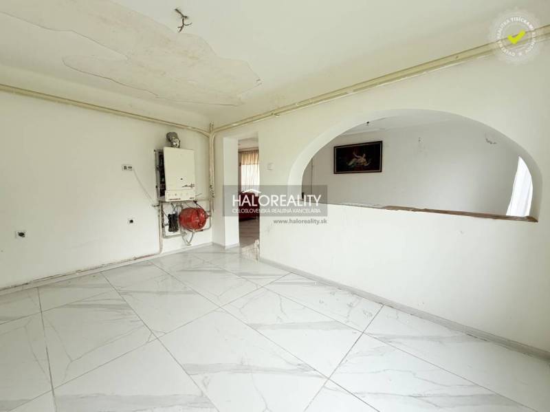 White room in a family house with tiles and an arched passage.