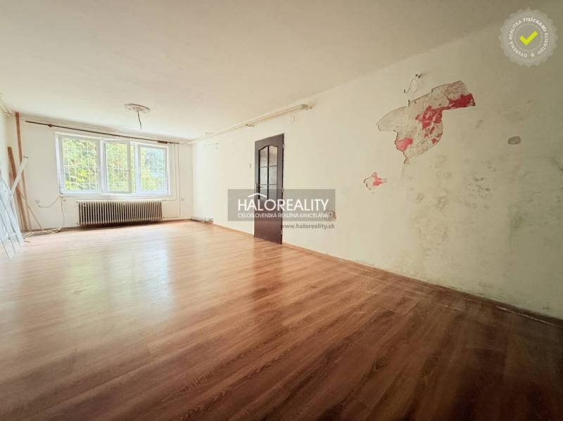 A spacious room with a wood-patterned floor and a large window in a family house.