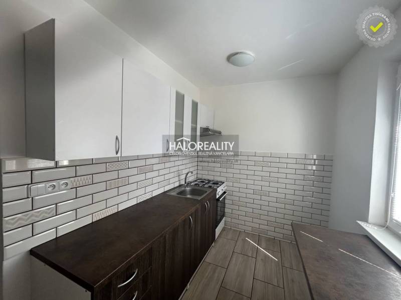 The kitchen in the 3-room apartment has ceramic tiles and a floor with a wooden decor.