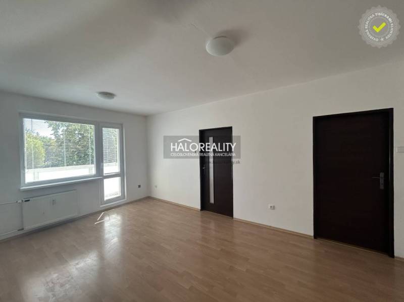 Bright living room in a 3-room apartment with wood-patterned flooring and a large window.