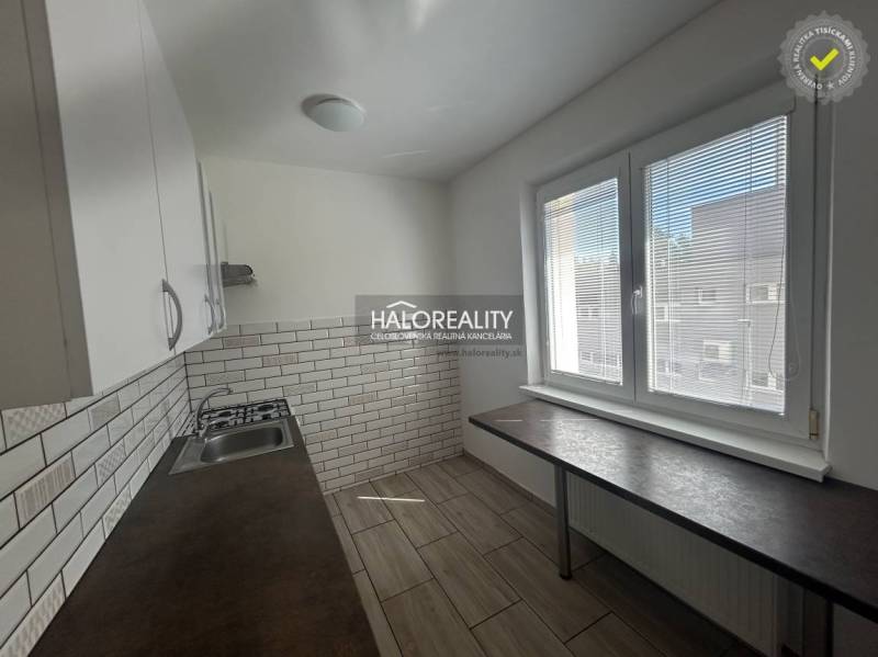 A kitchen in a 3-room apartment with white cabinets and textured tiles.