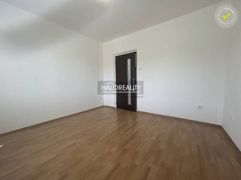 An empty room in a 3-room apartment with a wood-patterned floor and dark doors.