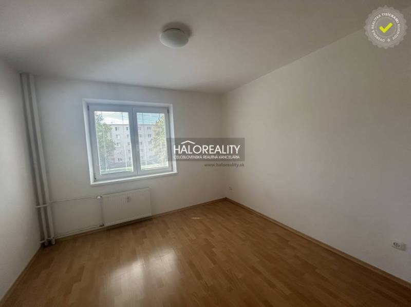 A room in a 3-room apartment with white walls and a floor with a wood decor.