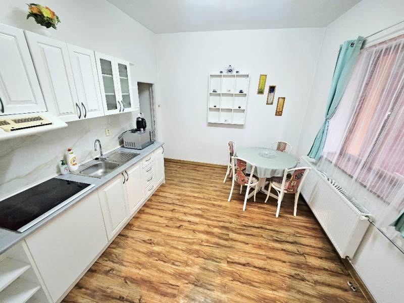 A kitchen in a family house with a wooden decor floor, a table, and white cabinets.