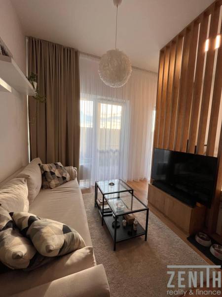 Living room with a comfortable sofa, glass table, and wooden-patterned floor.
