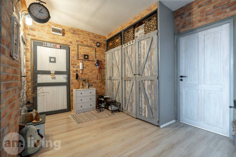 Entrance hall in a 3-room apartment with brick walls and a wooden decor floor.