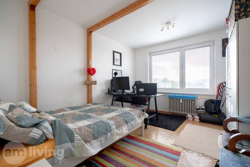 A bedroom with a desk and a decorated floor in a 3-room apartment.