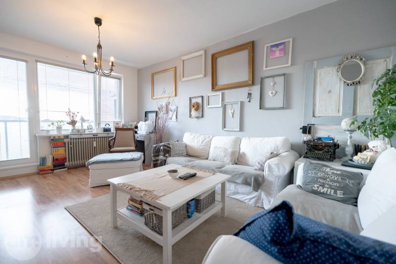 Living room with a comfortable sofa, wood-patterned flooring, and wall decorations.