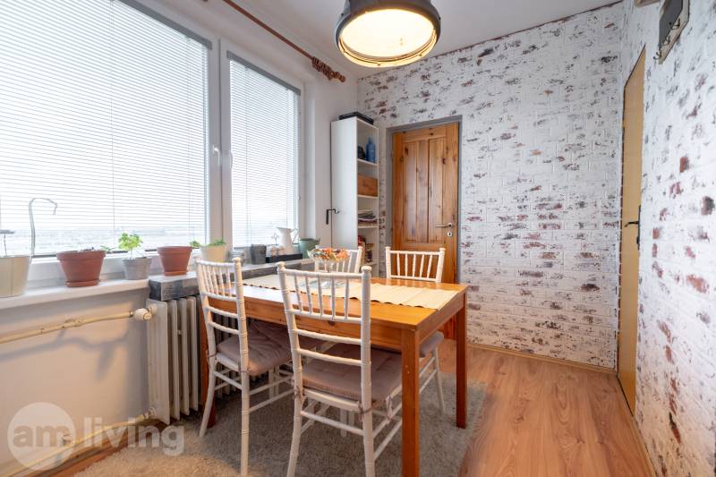 Dining area in a 3-room apartment with a brick wall and a wooden decor floor.