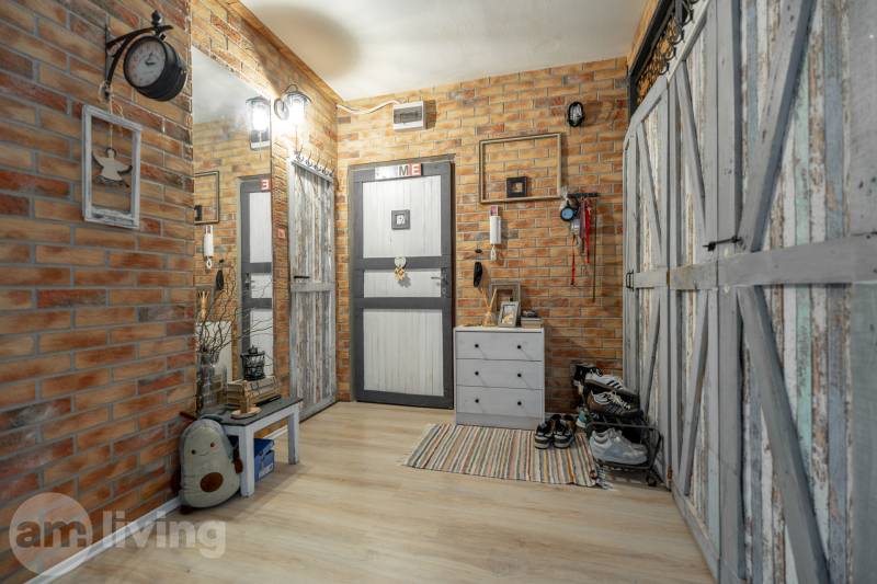 A hallway of a 3-room apartment interior with brick walls and a wooden decor floor.