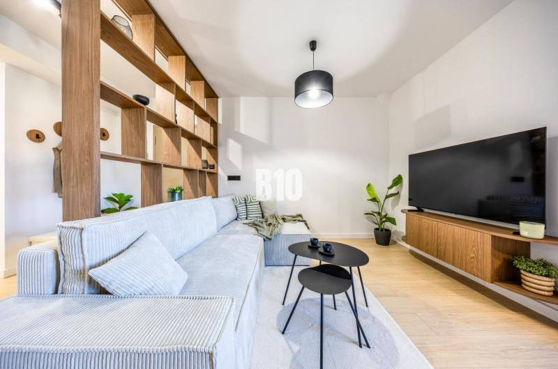Living room in a 3-room apartment with a sofa, television, and wooden decor.