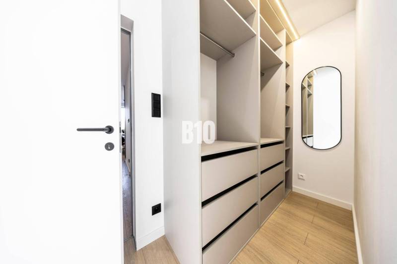 Built-in wardrobe in a 3-room apartment with a wooden decor floor and a mirror.