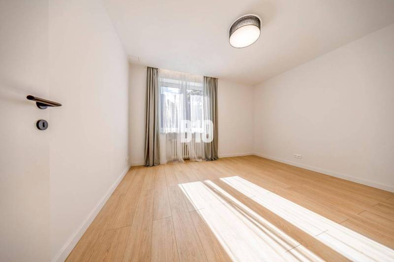 A room with a wooden floor decor, curtains, and a window in a 3-room apartment.