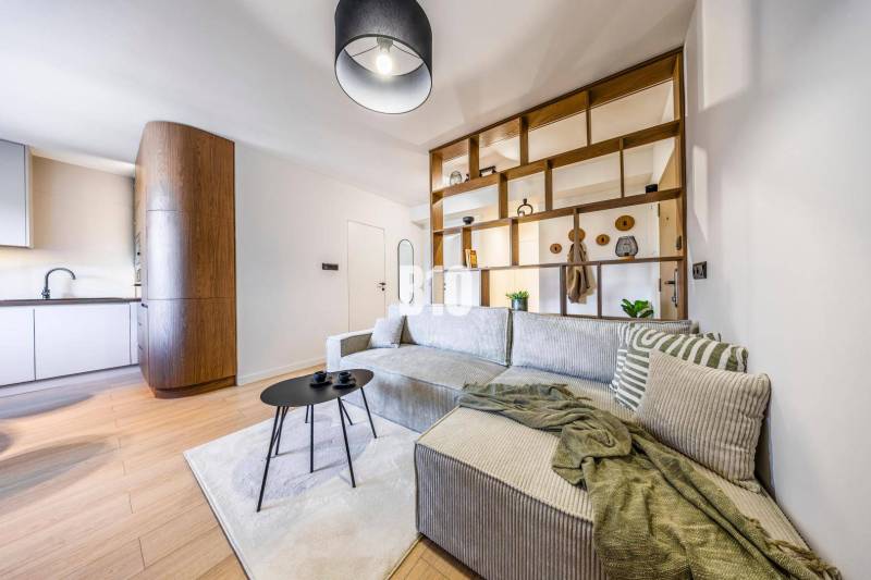 Living room in a 3-room apartment with a bed and a wooden decor floor.