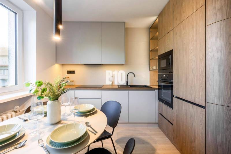 A kitchen of a 3-room apartment with a dining table and a wooden-patterned floor.