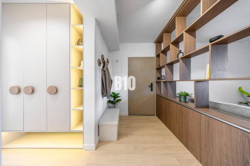 Entrance hall with wooden decor, white cabinets, and a shelf in a 3-room apartment.