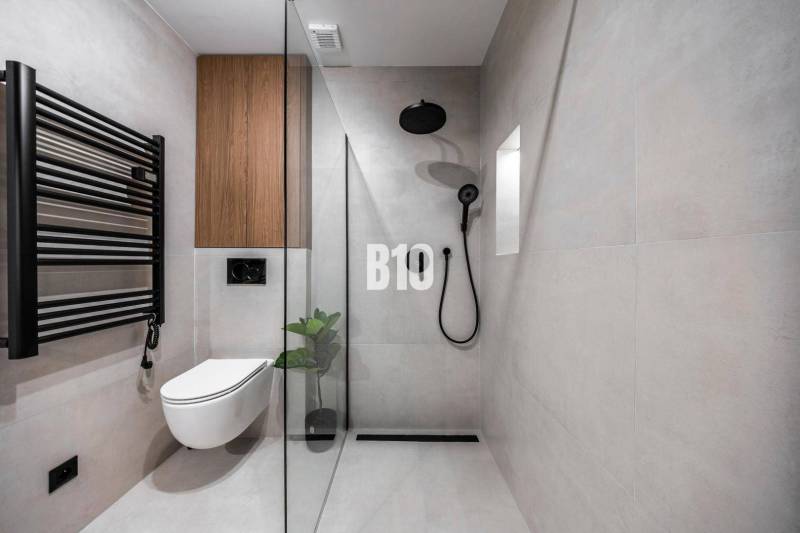 A minimalist bathroom with a toilet, shower, and black accessories in a 3-room apartment.