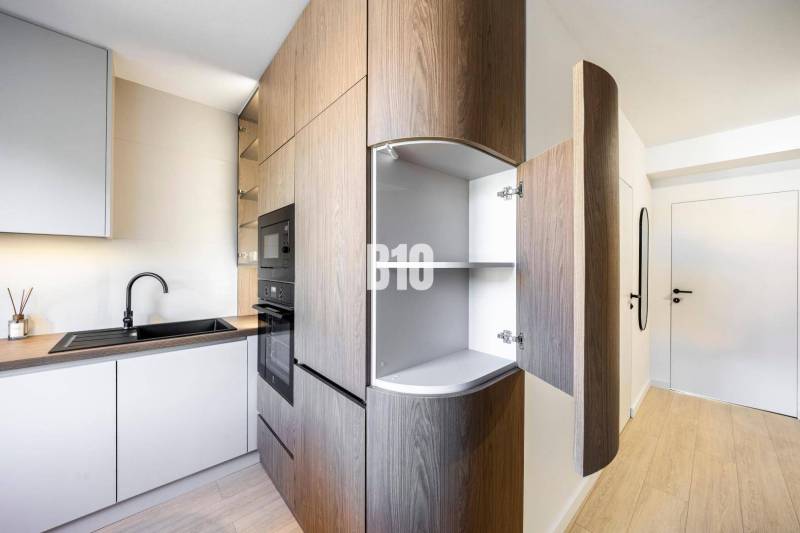 A kitchen in a 3-room apartment with a wooden decor floor and built-in appliances.