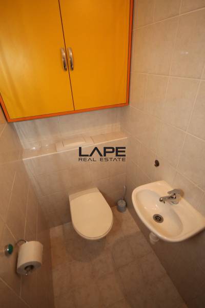 A toilet in a one-room apartment with a chrome holder and a yellow cabinet on the wall.