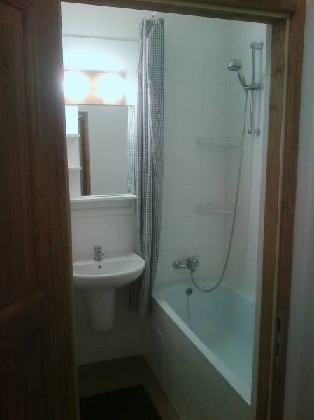 A bathroom with a bathtub and a sink in a studio apartment, reaching up to the ceiling.