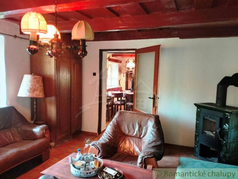 Living room in a cottage with leather armchairs, a wood-burning stove, and wooden decor.