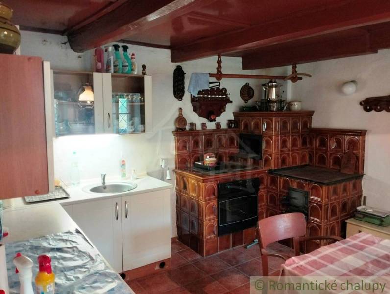 A kitchen with a tiled stove, a wooden-patterned floor, and a sink on a white counter.