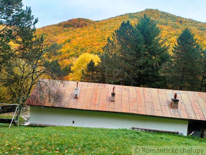 A cottage in Chocholná-Velčice surrounded by autumn forest and hills, a peaceful natural scenery.