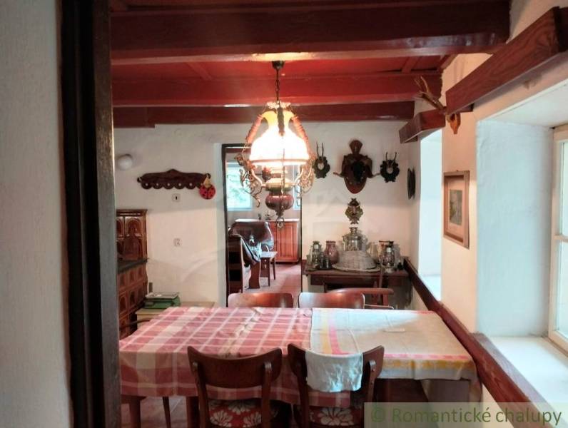 Dining room in a cottage with a wooden ceiling, decorations, and a set table.